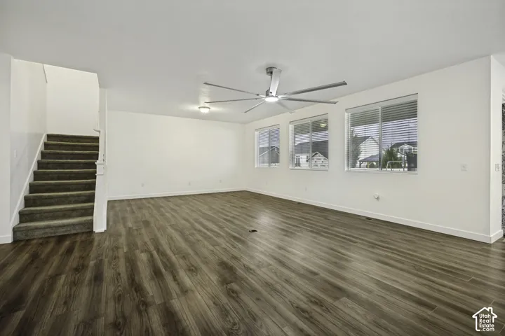 Spacious living area featuring wood-finish flooring, multiple windows with blinds, a modern ceiling fan, and recessed lighting