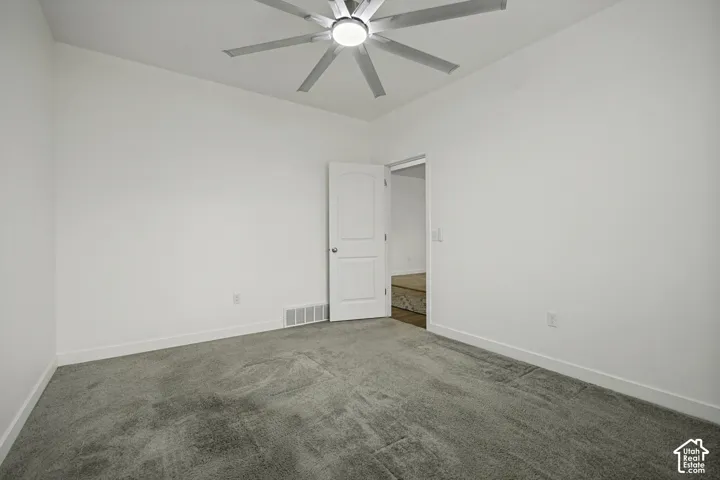 Gray carpeted flooring, white painted walls, white trim, recessed lighting, and a ceiling fan