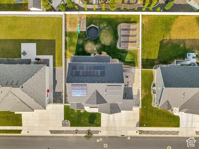 Solar panel array, shingle roofing, paved driveway, concrete walkways, and green lawn