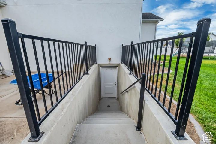 Exterior basement access with concrete steps, black metal railings, and a solid exterior door