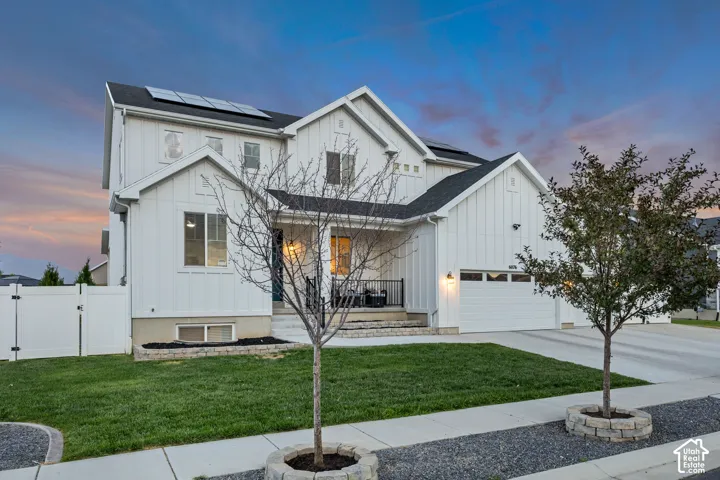 Modern farmhouse exterior with white board and batten siding, black shingle roofing, and solar panels