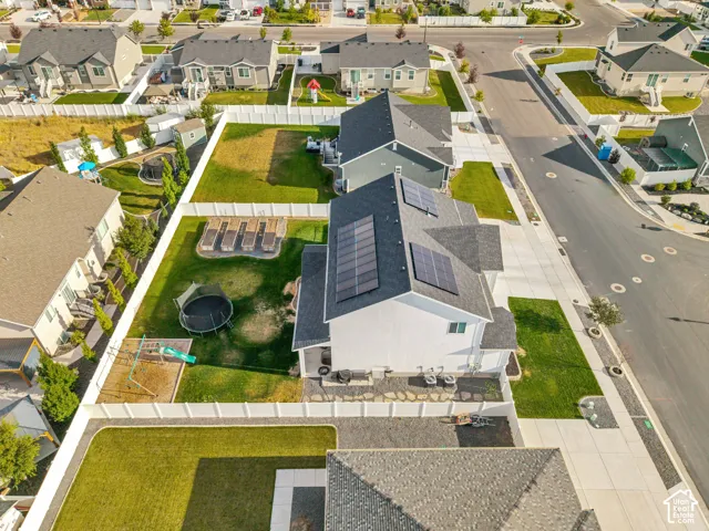 Property featuring a white fence, green lawn, solar panels, and a paved driveway