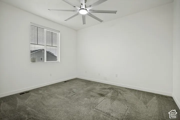 Spacious room featuring a window with blinds, a ceiling fan with integrated lighting, and neutral carpeting