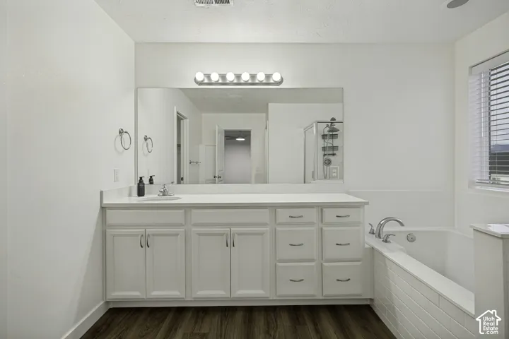 White vanity with dual sinks, a large mirror, and overhead strip lighting