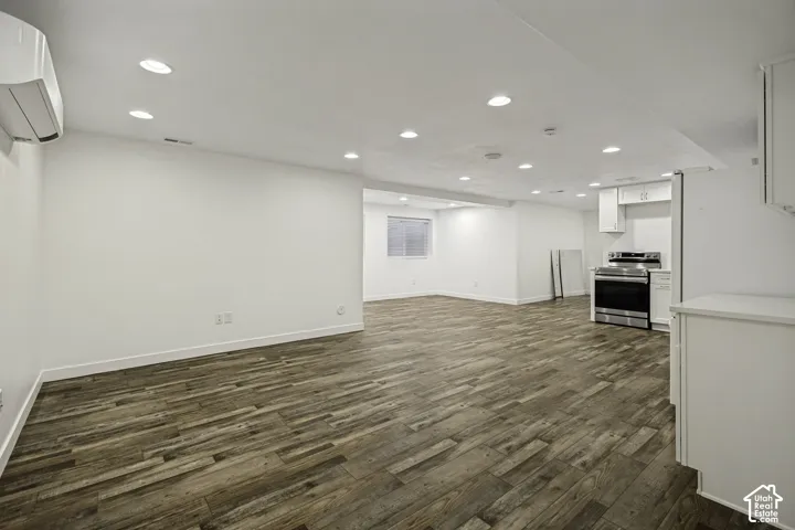 Expansive open-concept living space with wood-finish flooring, recessed lighting, and a split air conditioning unit