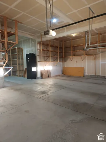Concrete floor garage featuring extensive built-in wooden shelving and an automatic garage door opener