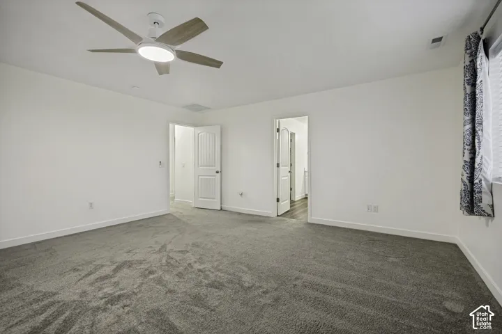 Spacious room featuring neutral carpeting, a ceiling fan with integrated lighting, and crisp white walls