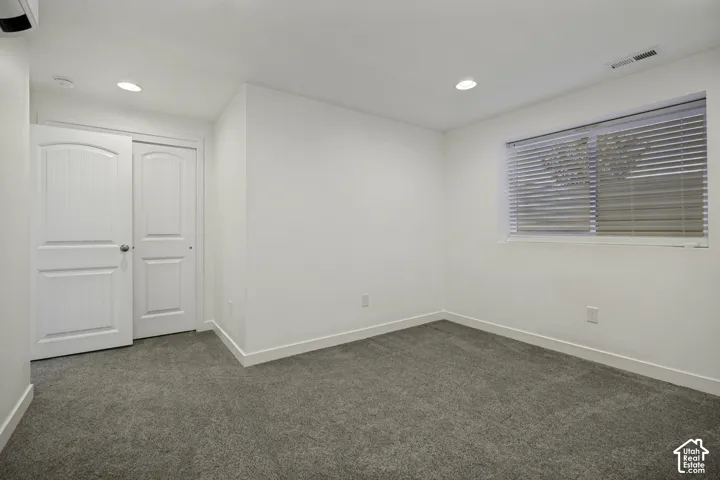 Neutral wall paint, gray carpet, recessed ceiling lighting, window with blinds, and white panel doors