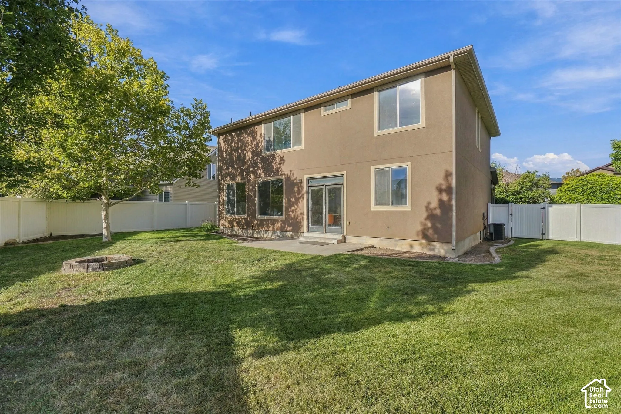 Expansive backyard with a manicured lawn, concrete patio, and built-in fire pit