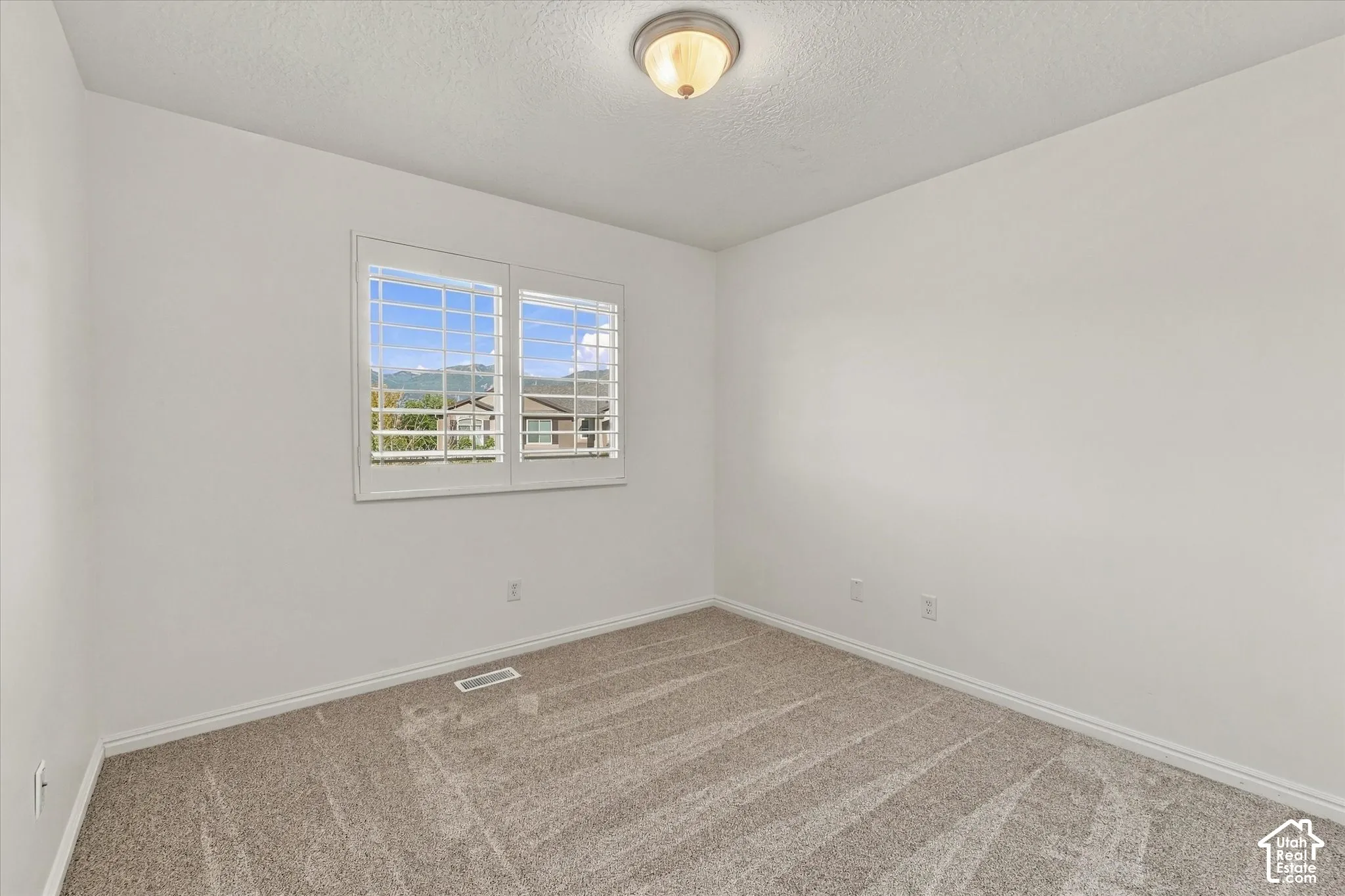 Neutral wall finishes, recessed window with white plantation shutters, neutral carpet flooring, and a flush mount ceiling light