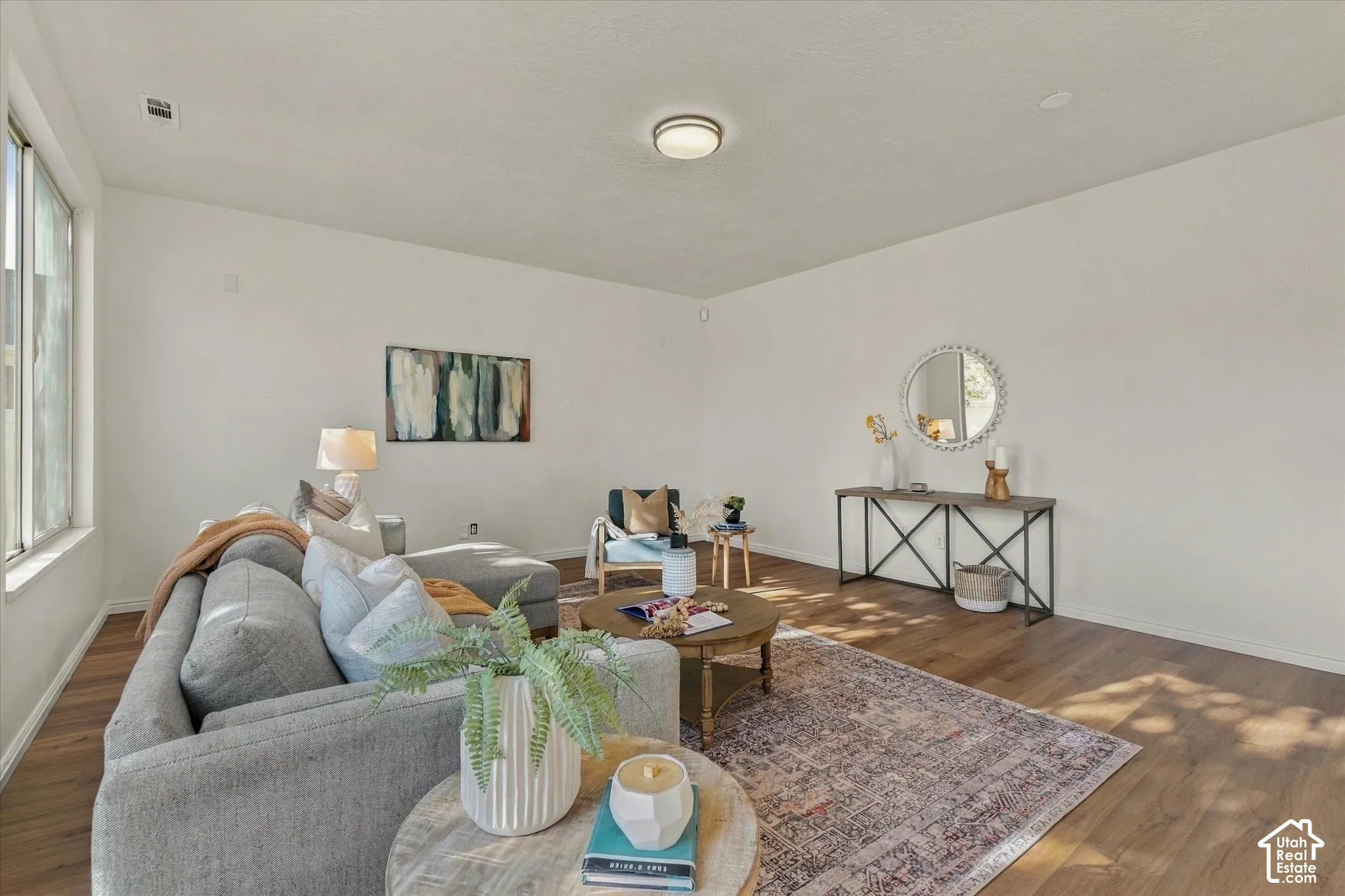 Spacious living area featuring large windows, wood-finish flooring, and crisp white walls