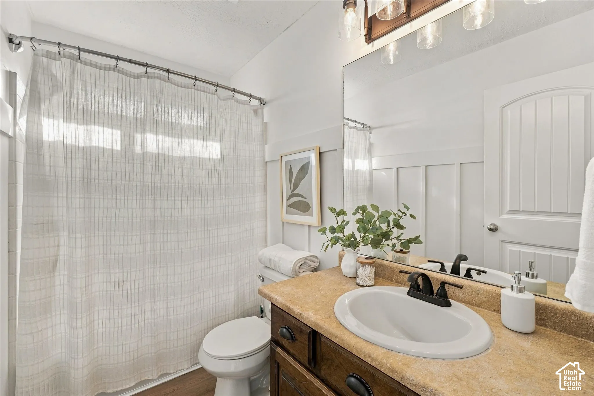Bathroom featuring a vanity with an oval sink, dark wood-finish cabinetry, a large mirror, and board-and-batten wall detailing