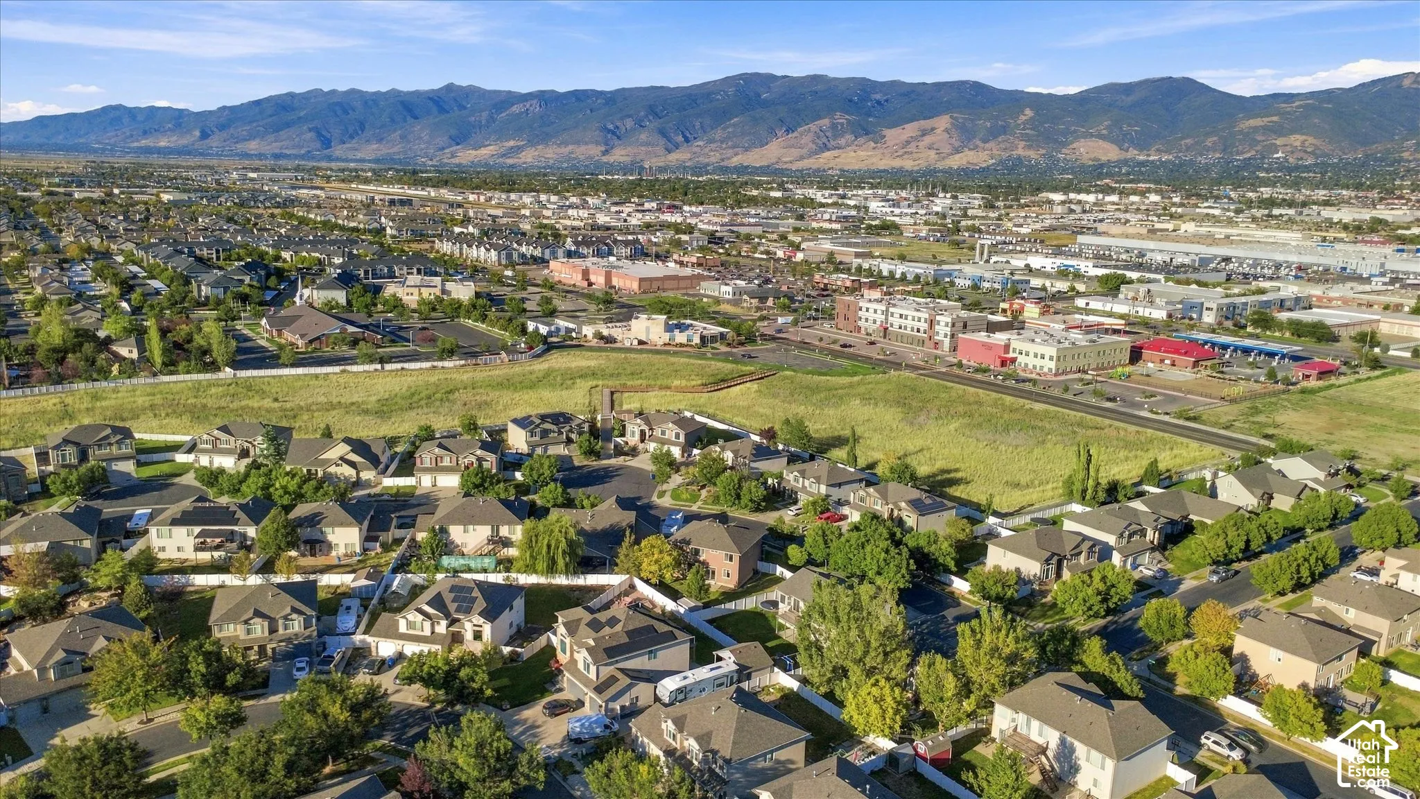 Expansive residential area with mountain backdrop, featuring a mix of single-family residences, commercial structures, and open green spaces
