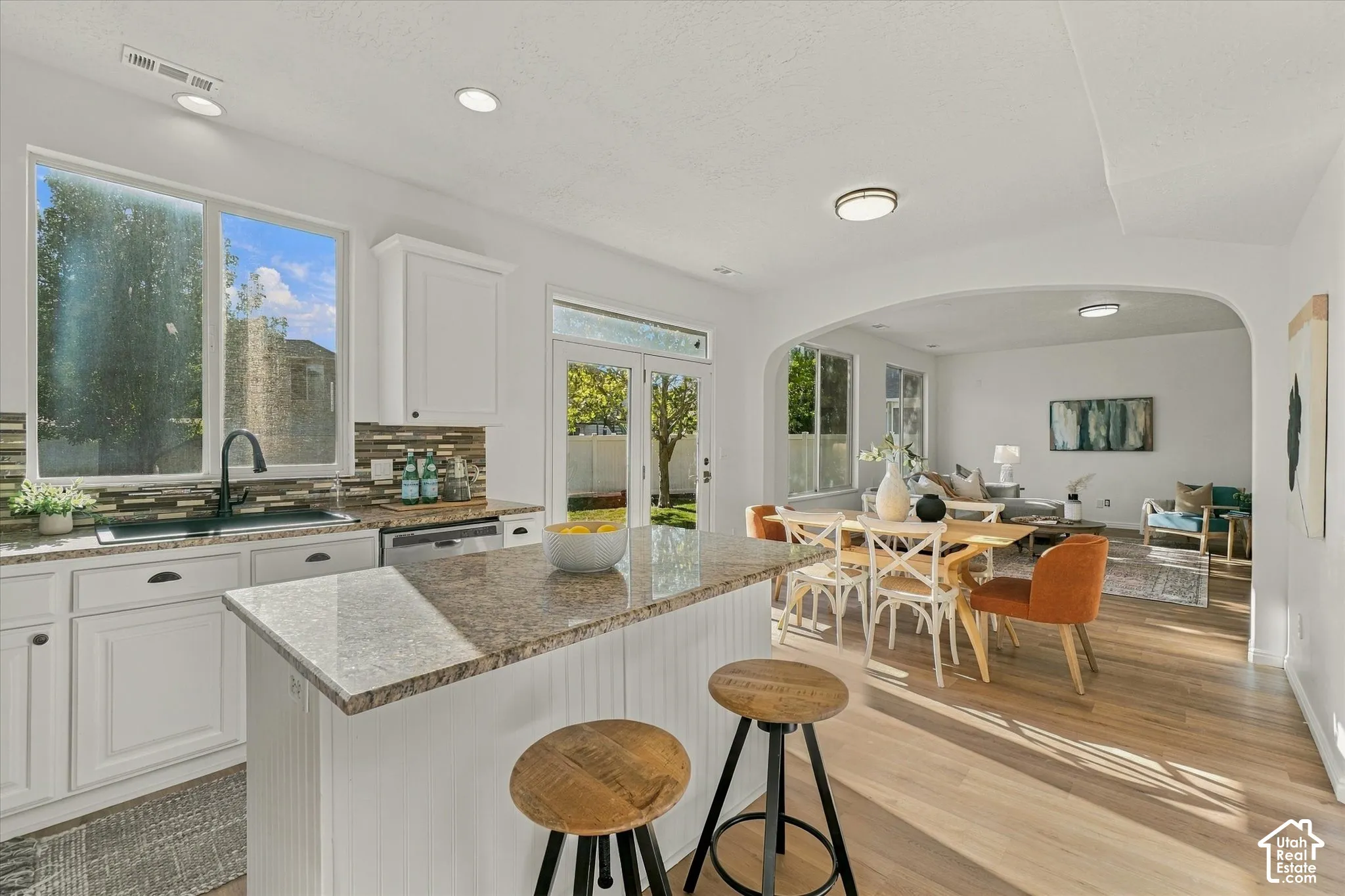 Kitchen featuring white cabinetry, a composite stone countertop, and a tiled backsplash