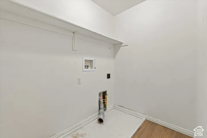 Laundry area featuring a wall-mounted shelf, utility hookups, and wood-finish flooring