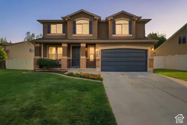 Two-story residence with a front porch, an attached garage, and a concrete driveway