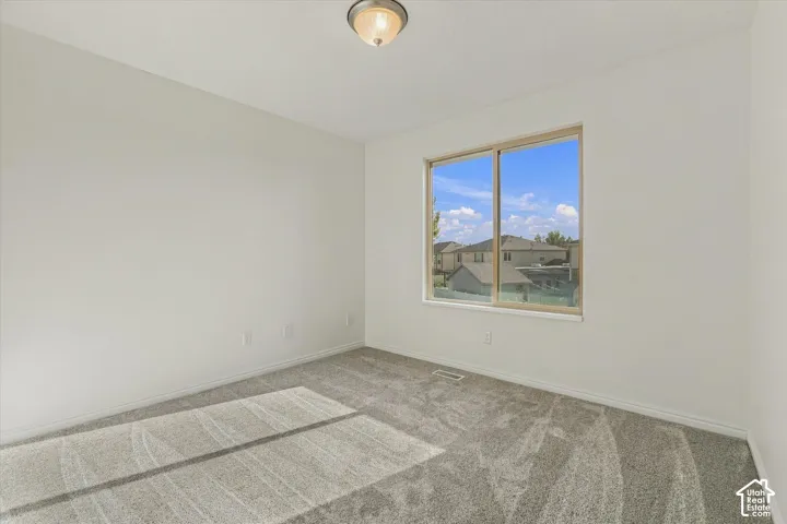 Neutral-toned walls, recessed lighting, carpeted flooring, and a large window