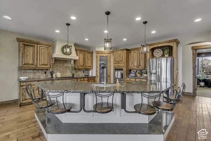 Kitchen featuring a multi-level island with seating, stainless steel appliances, wood-finish cabinetry, and recessed lighting