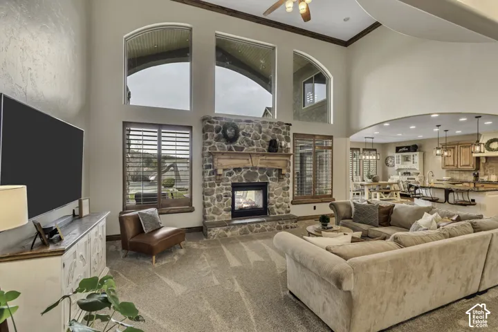 Two-story living area featuring a stone-clad fireplace, wood mantel, and arched windows