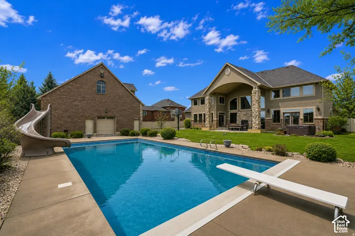 Rectangular swimming pool with diving board, concrete surround, and attached slide