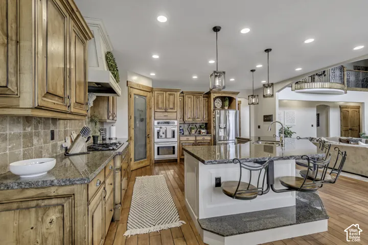 Well-appointed kitchen featuring wood cabinetry, granite countertops, tile backsplash, built-in double ovens, and recessed lighting