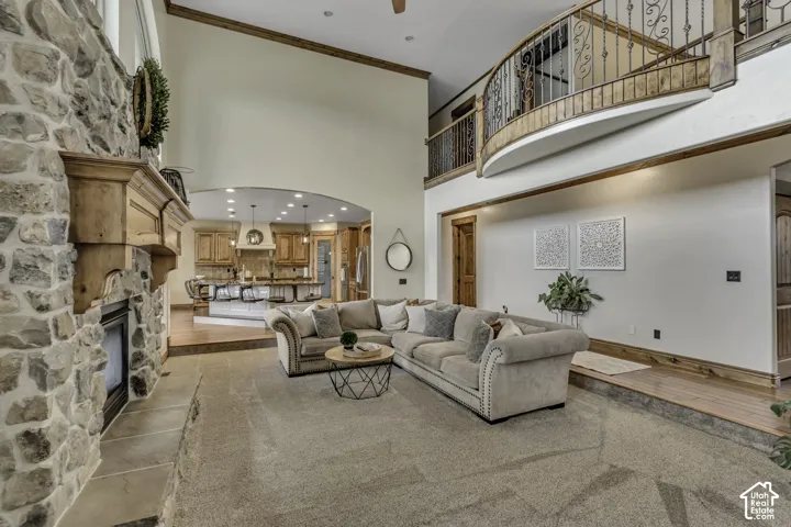 Vaulted ceilings, a stone-clad fireplace with wood mantle, a wood-finish balcony with wrought iron railing, and a kitchen with recessed lighting and a central island