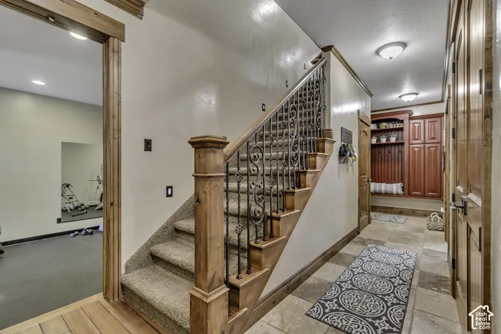 Staircase with wrought iron balusters and wood newel posts, carpeted treads, and wood stringers