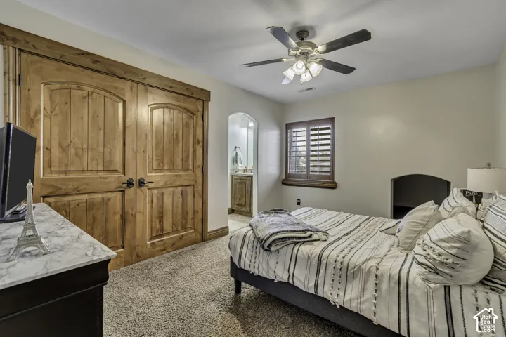Wood-finish double doors, ceiling fan, window with wood shutters, and carpeted flooring