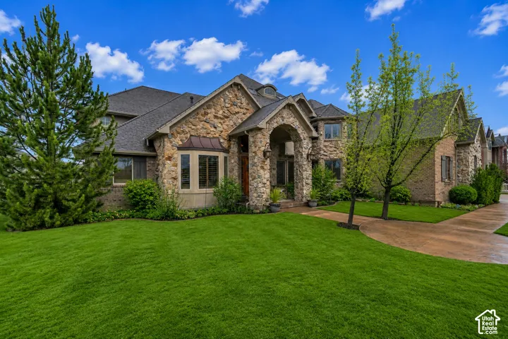 Stone and brick exterior with a prominent arched entry, bay window with copper-finish detailing, and a multi-pitch roofline