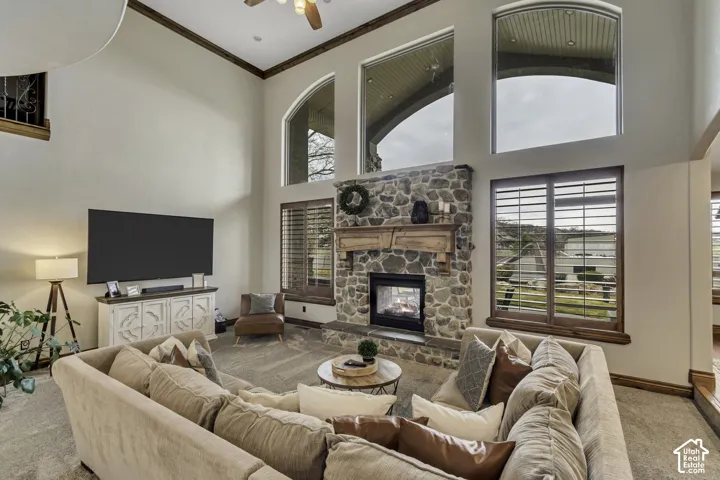 Great room with high ceilings, featuring a stacked stone fireplace with a wood mantel