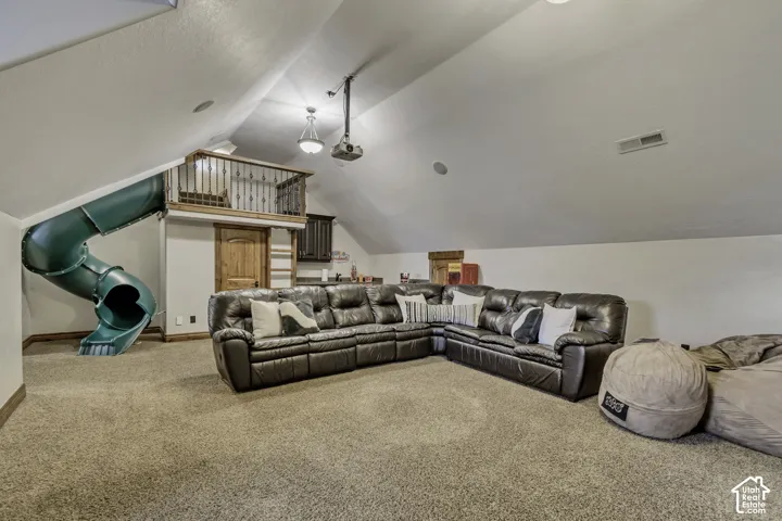 Carpeted room featuring a built-in slide, elevated loft with railing, wood-finish door, and integrated projector