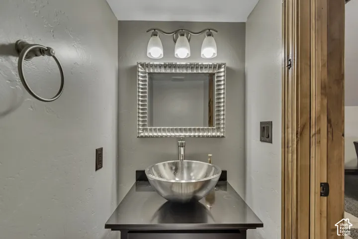 Modern vessel sink with a black countertop, framed mirror, and brushed nickel fixtures