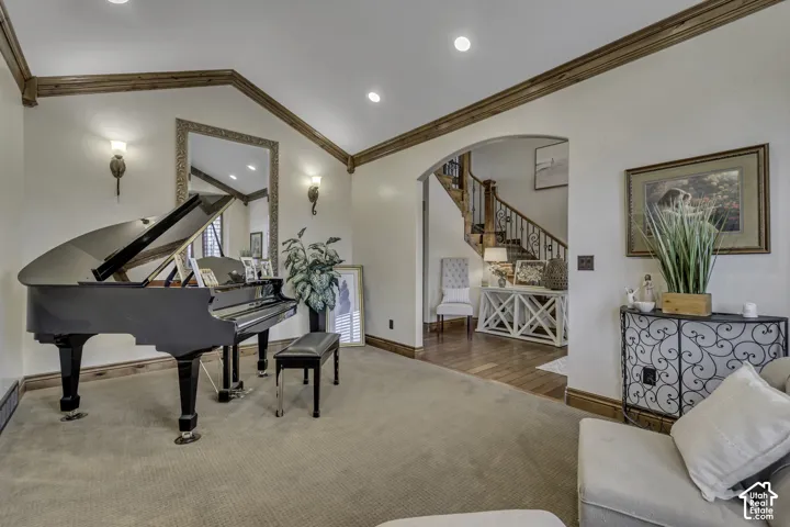 Vaulted ceiling with wood beam accents, recessed lighting, and wall sconces