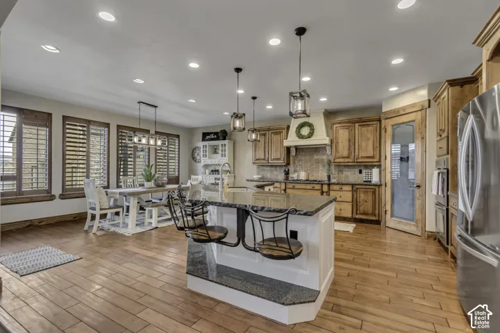 Kitchen featuring wood-finish flooring, recessed lighting, wood cabinetry, and a center island with bar seating