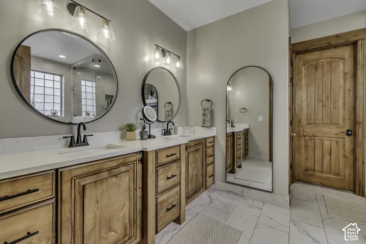 Double vanity with wood-finish cabinetry, white countertops, and matte black hardware