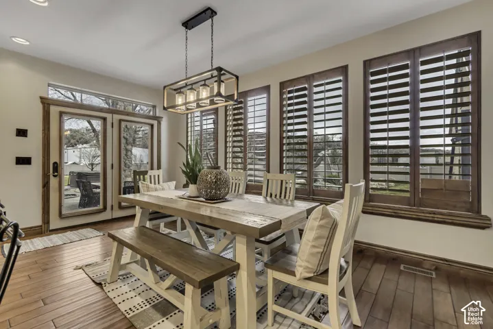 Wood-finish flooring throughout, custom wood plantation shutters, double French doors with transom window, and a modern linear chandelier