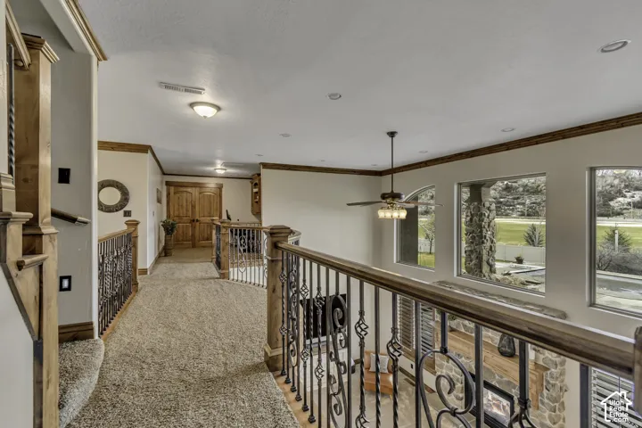 Spacious upper landing with carpeted flooring, decorative wrought iron railings, and wood-finish trim