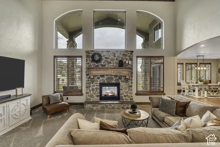 Vaulted ceilings featuring arched windows, stone-clad fireplace with wood mantel, hardwood flooring in dining space, and built-in window seating