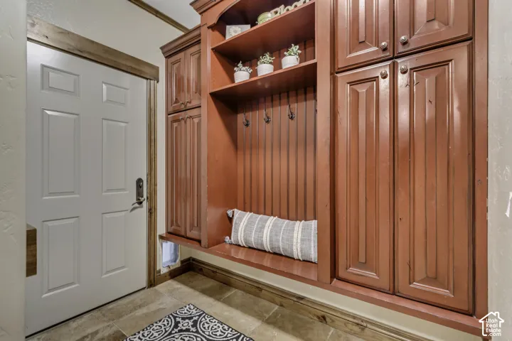 Custom built-in cabinetry with open shelving and storage, accentuating a paneled white door with wood trim, and tile flooring