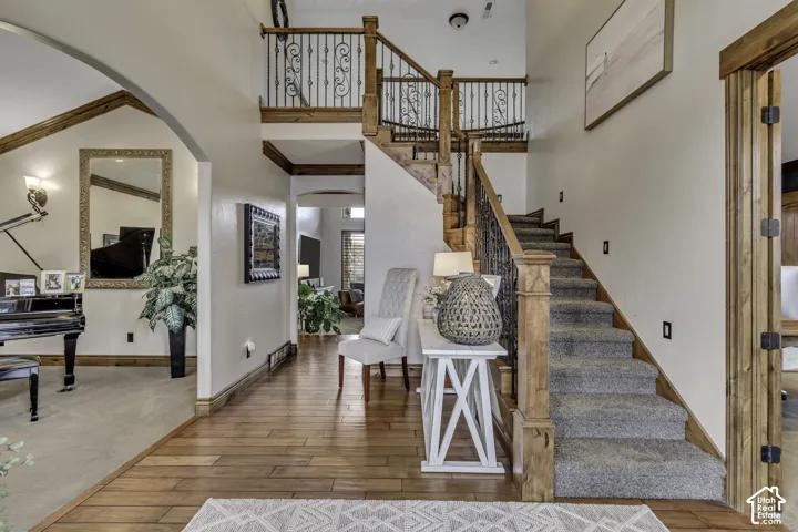 Hardwood flooring with staircase featuring carpeted treads and wrought iron balusters