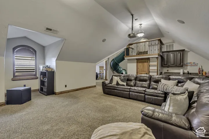 Sloped ceilings with recessed lighting, integrated projector system, built-in entertainment bar with cabinetry, and a carpeted floor