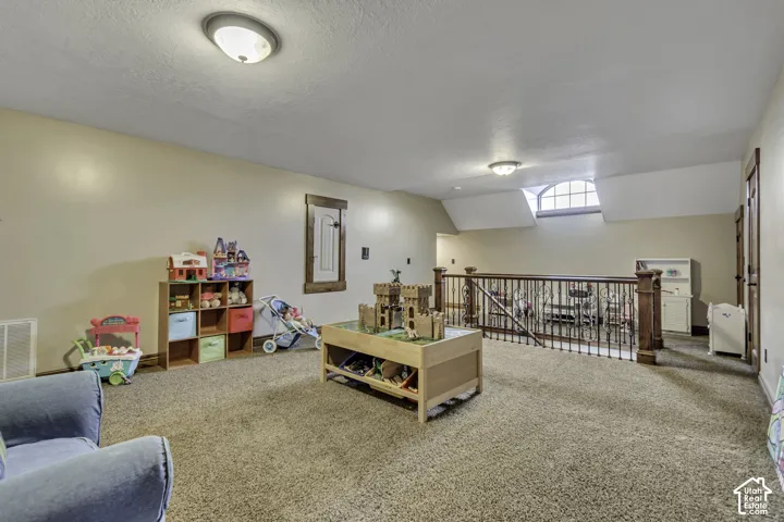 Carpeted loft area featuring a wood-finish railing, built-in window with arched transom, and recessed lighting