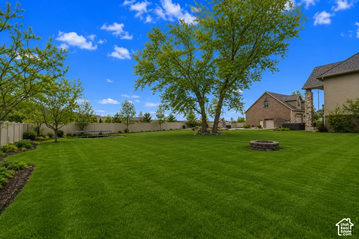 Expansive green lawn with mature trees and a stone-built fire pit