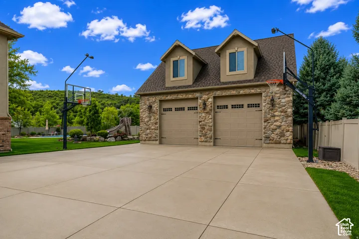 Two-car garage featuring stone facade, dormer windows, and carriage-style doors