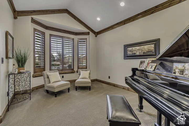 Bay window with wood plantation shutters, vaulted ceiling with exposed wood beams, recessed lighting, and carpeted flooring