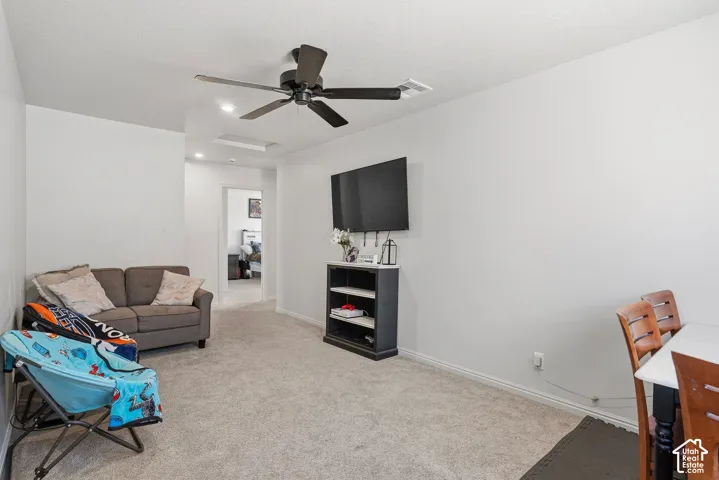 Neutral wall colors, carpeted flooring, and a ceiling fan with integrated lighting