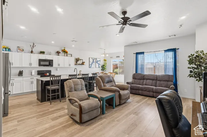 Open-concept living space with wood-finish flooring, recessed lighting, and a ceiling fan