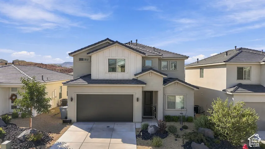 Contemporary two-story residence featuring a dark tile roof, board and batten facade accents, stucco exterior, and an attached two-car garage