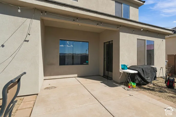 Covered patio with concrete flooring, stucco exterior, and multiple windows