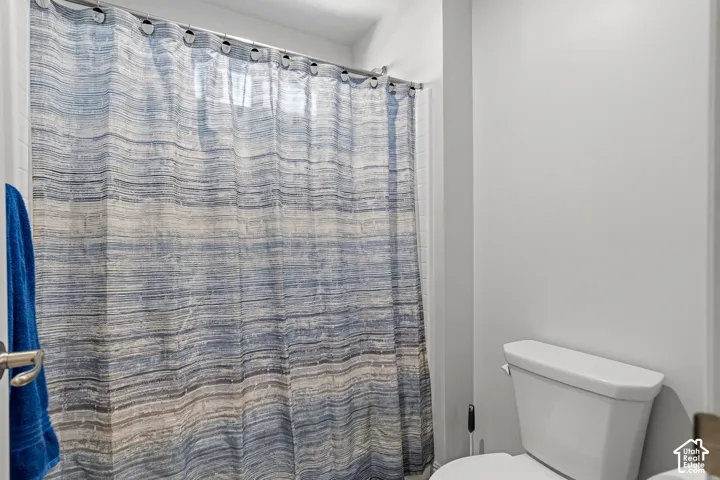 White wall paint, white toilet, and a shower curtain rod